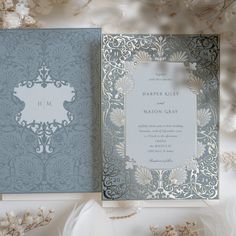 a wedding card with an ornate design on the front and back, sitting next to some dried flowers