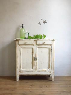 an old white cabinet with green plants on top and stars painted on the wall behind it