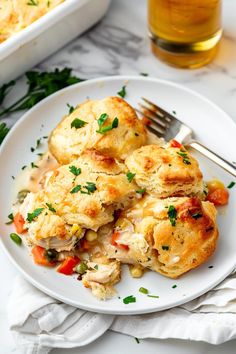 a white plate topped with chicken pot pies next to a glass of beer and a fork