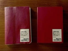 two red notebooks sitting on top of a wooden table