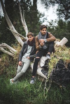 two young men sitting on a tree stump