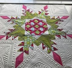 a close up of a quilt on a table with pink, green and white designs