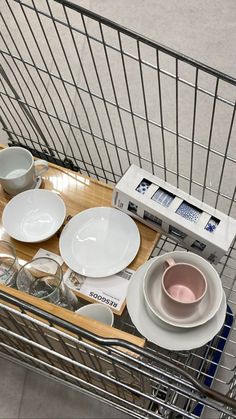 a shopping cart filled with plates and bowls sitting on top of a wooden table next to a microwave