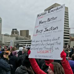 a group of people holding up signs in the middle of a street with buildings in the background