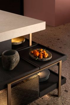 a bowl of oranges on a table with plates and bowls in the center area