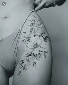 a black and white photo of a woman's stomach with flowers tattooed on it