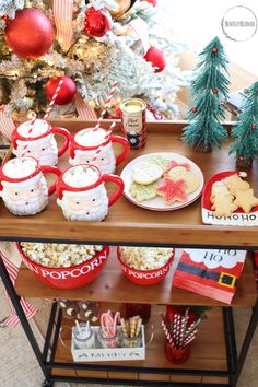 a table topped with lots of food next to a christmas tree filled with ornaments and decorations