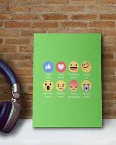 a green canvas with emoticions on it next to headphones and a brick wall