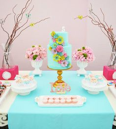 a blue table topped with a cake and cupcakes