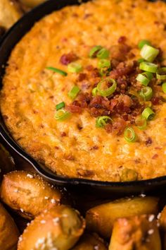 a black bowl filled with cheese and bacon dip surrounded by other baked potato wedges