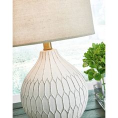 a table lamp sitting on top of a wooden table next to a potted plant