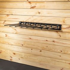 a wooden wall with some metal bars hanging from it's sides and wood planks on the side