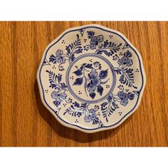 a blue and white plate sitting on top of a wooden table next to a wall