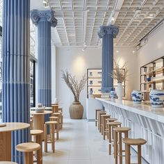 the interior of a restaurant with blue and white columns, wooden tables and stools