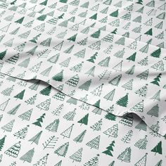 a green and white christmas tree print sheet set on top of a bed with the sheets pulled down