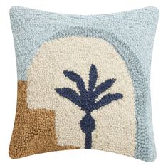 a blue and white pillow with an embroidered palm tree on it