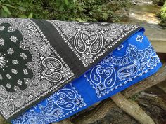 two blue and black bandanas sitting on top of a wooden bench next to trees