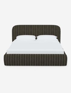 an upholstered bed with white sheets and brown pinstripe fabric headboard