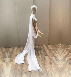 a mannequin dressed in white is standing on a wooden floor