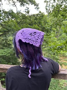 a woman with purple hair wearing a crocheted hat