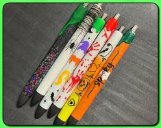 four pens with different designs on them sitting next to each other in front of a green frame