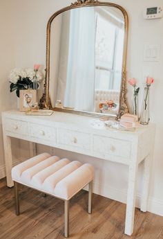 a dressing table with a mirror, stool and flowers