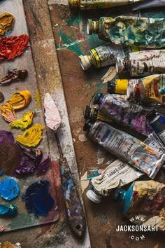 an artist's palette with paint, brushes and other art supplies sitting on top of it