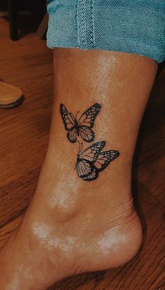 a woman's foot with two butterflies tattoo on the side of her leg,