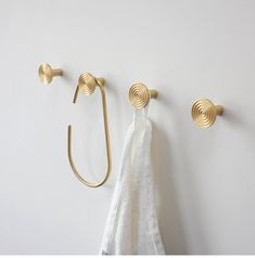 two gold hooks on the wall next to a white towel