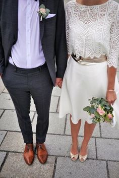 a man and woman standing next to each other on a brick walkway with flowers in their hands