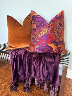 two colorful pillows sitting on top of a wooden table