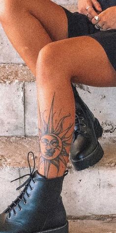 a woman sitting on the steps with her legs crossed and tattoos on her leg, wearing black combat boots