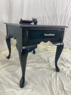 a black table with drawers and legs on it's side, sitting on a white sheet