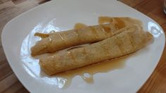 two crepes sitting on top of a white plate covered in caramel sauce