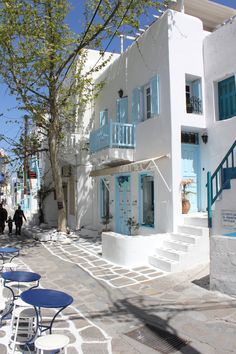 a white building with blue shutters on the front and stairs leading up to it