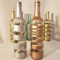 three bottles are lined up on a white tablecloth with gold and silver foil strips