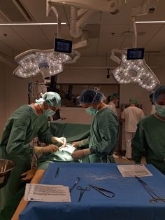 doctors performing surgery in an operating room with lights on and medical equipment hanging from the ceiling