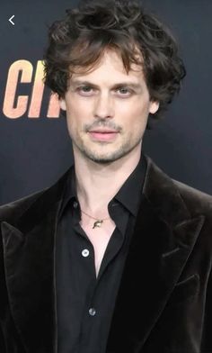 a man with curly hair wearing a black suit