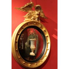 a mirror hanging on the wall with an eagle statue in it's centerpiece