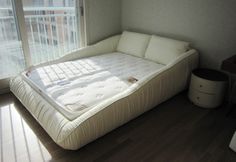 a bed sitting in the corner of a room next to a window with blinds on it