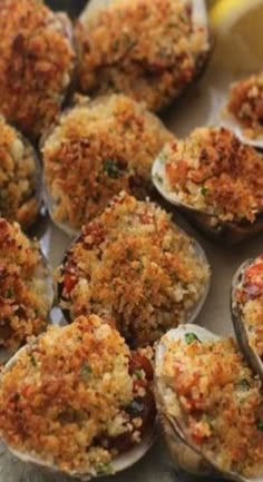 several cooked oysters with parmesan cheese and lemon wedges on the side