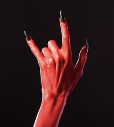 a woman's hand with black and red nail polish holding her fingers up in the air