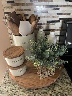 kitchen utensils are sitting on a wooden tray next to a potted plant