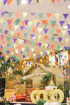 colorful flags hanging from the ceiling in an indoor market area with food and decorations on display