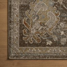 a brown and blue area rug with an ornate design on the center, surrounded by wood flooring