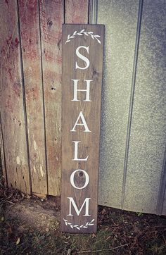 a wooden sign with the word shalom written in white on it next to a door