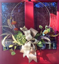 a red door with a wreath hanging on it's side and flowers in the middle