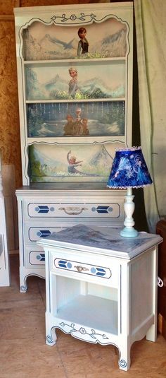 a white dresser with a blue lamp on it's top and an antique china cabinet in the background