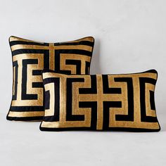 two black and gold pillows sitting next to each other