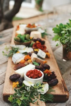 a long wooden table topped with lots of different types of cheeses and sauces